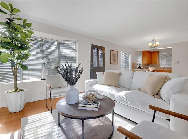 living area featuring baseboards, light wood-type flooring, and an inviting chandelier