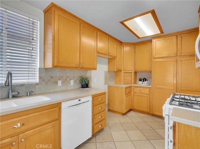kitchen with light tile patterned floors, a sink, light countertops, white appliances, and backsplash