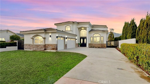 mediterranean / spanish house featuring a yard, stone siding, an attached garage, and fence