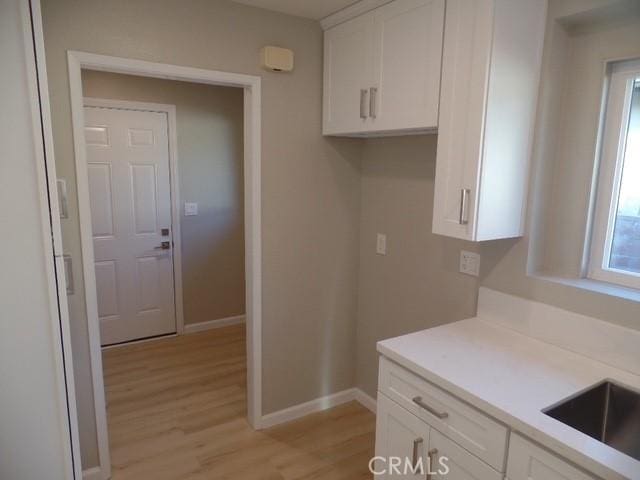 kitchen with white cabinetry, sink, and light hardwood / wood-style floors