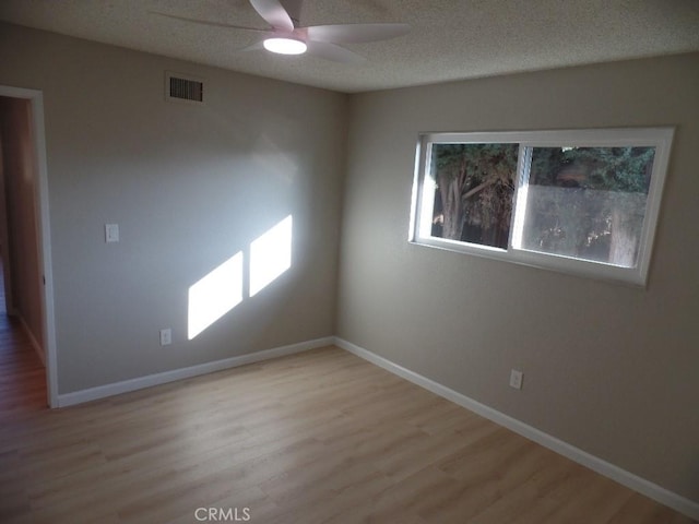 empty room featuring ceiling fan, a textured ceiling, and light hardwood / wood-style flooring