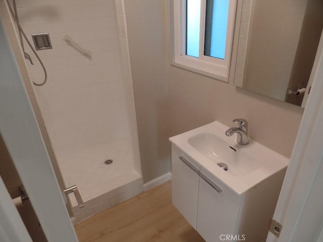 bathroom featuring hardwood / wood-style flooring, vanity, and tiled shower