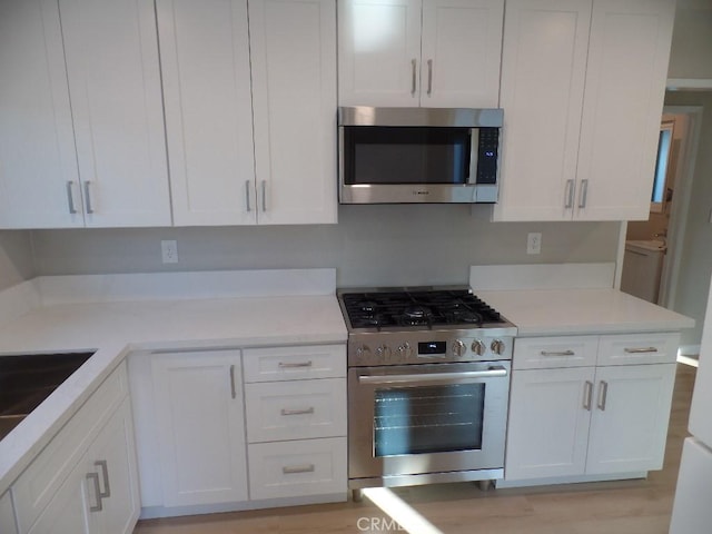 kitchen featuring sink, light hardwood / wood-style flooring, stainless steel appliances, and white cabinets