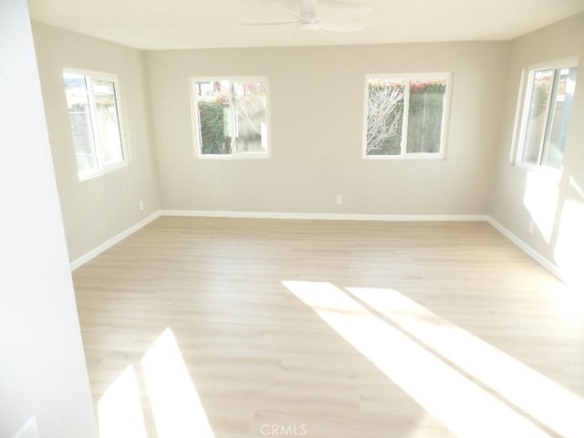 spare room with ceiling fan, plenty of natural light, and light hardwood / wood-style flooring