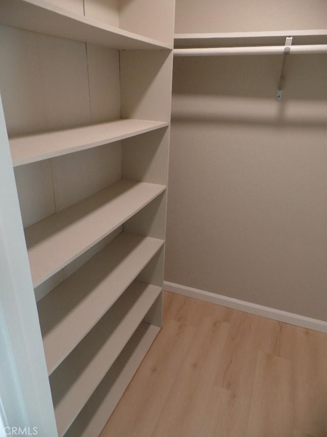 walk in closet with light hardwood / wood-style floors