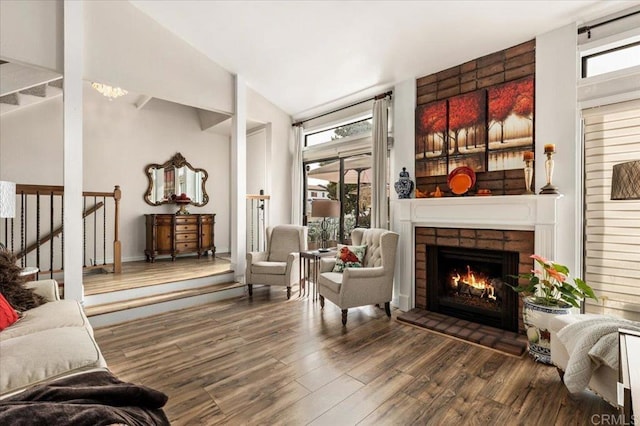 sitting room featuring stairway, a brick fireplace, and wood finished floors