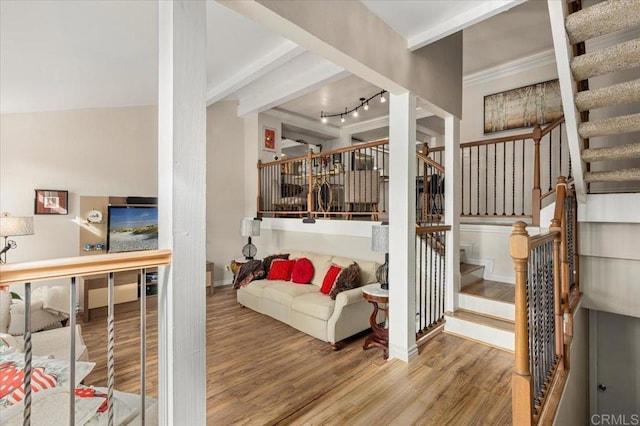 entryway featuring stairway, wood finished floors, baseboards, beam ceiling, and rail lighting