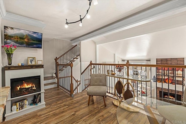 sitting room featuring crown molding, stairway, wood finished floors, and a warm lit fireplace