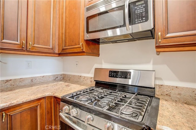 kitchen with light stone countertops and appliances with stainless steel finishes