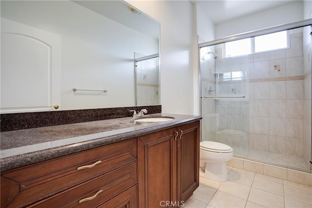 bathroom with tile patterned flooring, vanity, a shower with shower door, and toilet