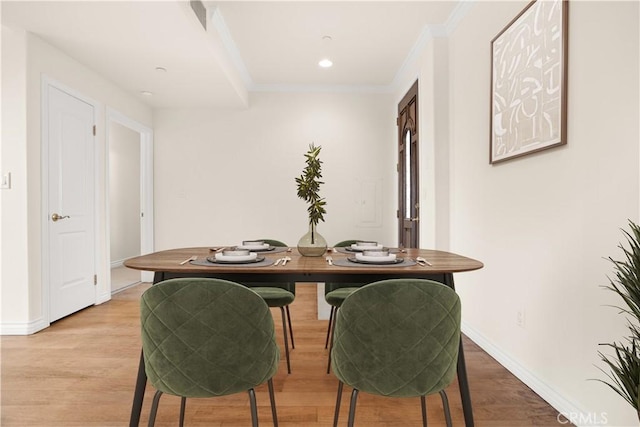 dining space with crown molding and light hardwood / wood-style flooring