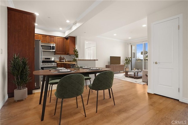 dining area featuring crown molding and light hardwood / wood-style flooring