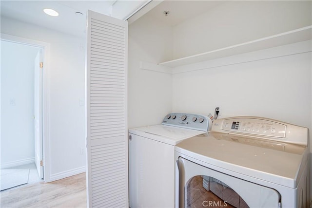 clothes washing area with washer and dryer and light wood-type flooring