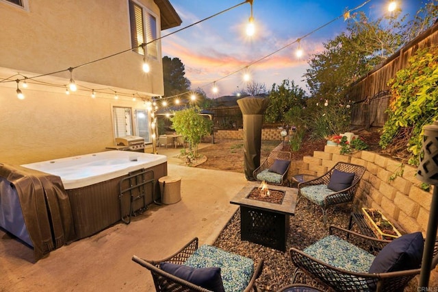 patio terrace at dusk featuring a hot tub, a grill, and an outdoor fire pit