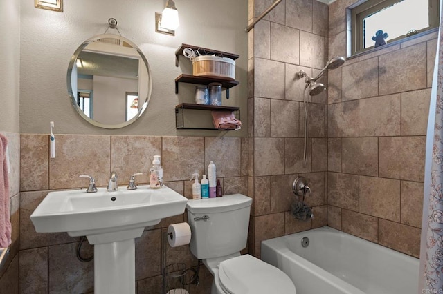 bathroom with shower / bathtub combination with curtain, toilet, and tile walls