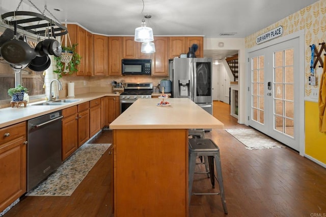 kitchen featuring a kitchen island, appliances with stainless steel finishes, sink, hardwood / wood-style flooring, and french doors