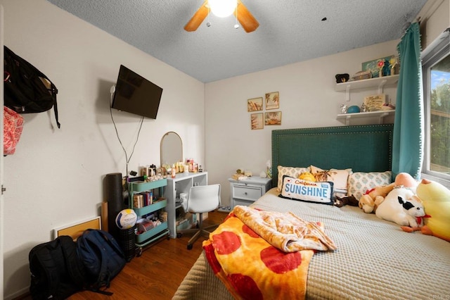 bedroom with ceiling fan, a textured ceiling, and dark hardwood / wood-style flooring