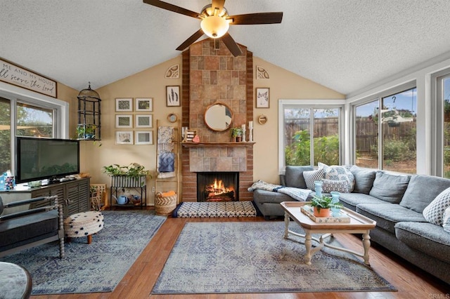 living room featuring wood-type flooring, a fireplace, vaulted ceiling, and a wealth of natural light