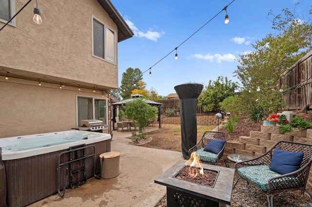 view of patio / terrace with grilling area, a hot tub, and an outdoor fire pit