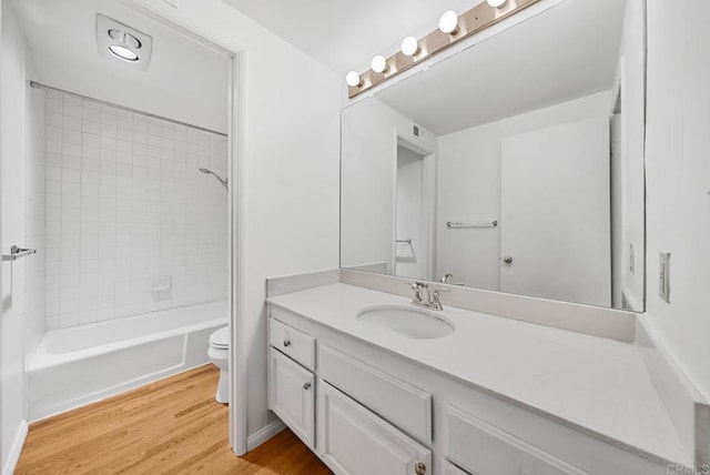 full bath featuring toilet,  shower combination, wood finished floors, and vanity