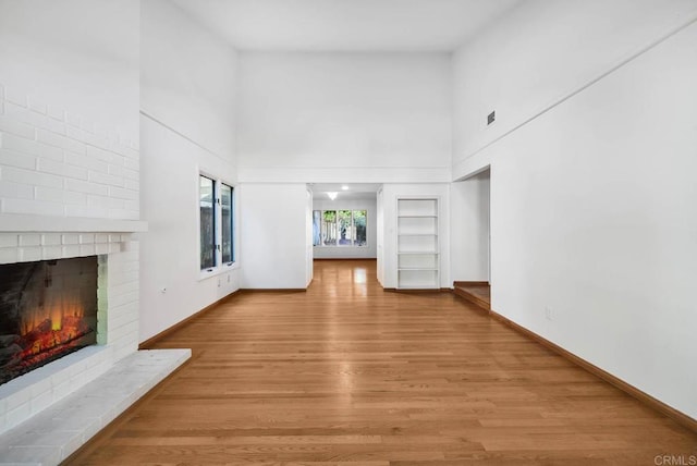 unfurnished living room with visible vents, a fireplace, light wood-style flooring, and baseboards