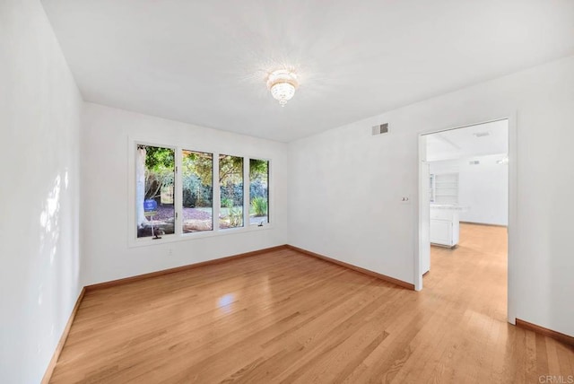 spare room with light wood-type flooring, baseboards, and visible vents