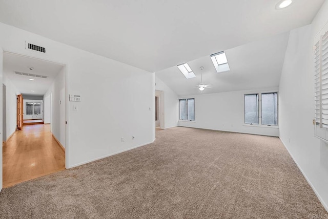 unfurnished room with vaulted ceiling with skylight, recessed lighting, visible vents, and light colored carpet