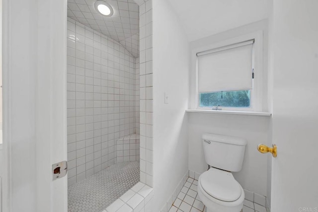 bathroom featuring tile patterned floors, baseboards, toilet, and a walk in shower