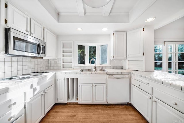 kitchen featuring tile countertops, a sink, white cabinets, dishwasher, and stainless steel microwave