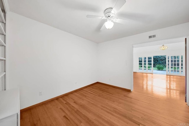 empty room with ceiling fan, wood finished floors, visible vents, and baseboards