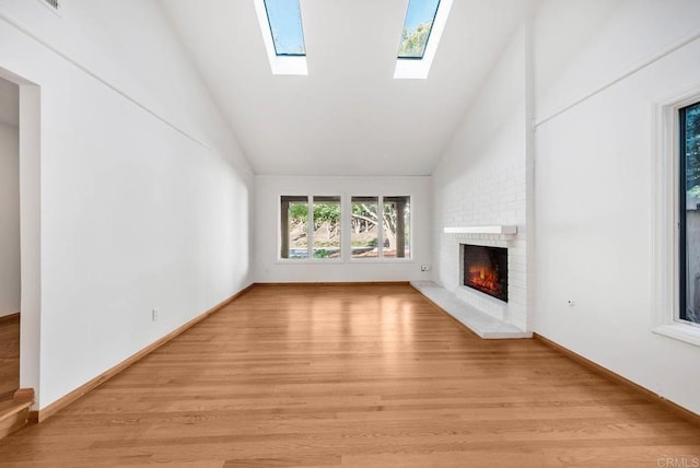 unfurnished living room featuring light wood-type flooring, lofted ceiling, a fireplace, and baseboards