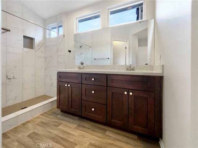 bathroom featuring hardwood / wood-style flooring, vanity, and tiled shower