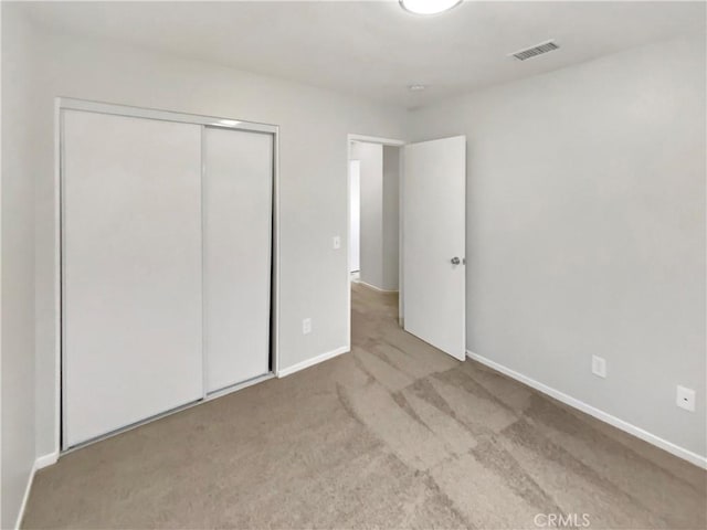 unfurnished bedroom with a closet and light carpet