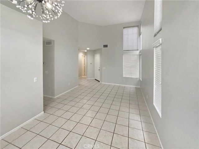 empty room with light tile patterned flooring and a chandelier