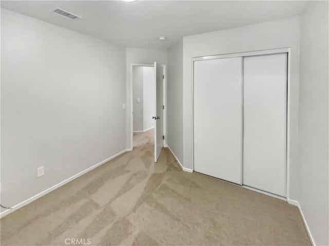 unfurnished bedroom featuring light colored carpet and a closet