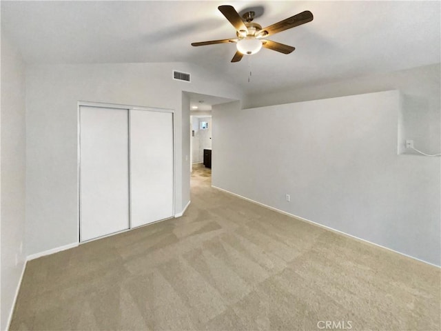 unfurnished bedroom with ceiling fan, vaulted ceiling, and light carpet