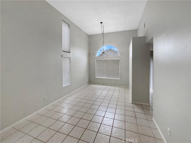 tiled empty room with a notable chandelier