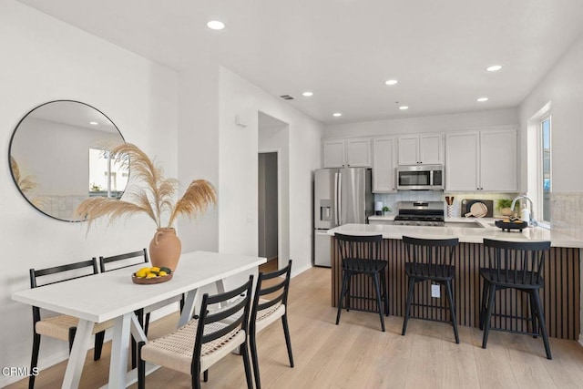 kitchen featuring a breakfast bar, white cabinets, decorative backsplash, kitchen peninsula, and stainless steel appliances