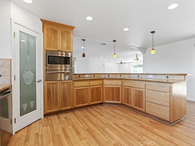 kitchen featuring light countertops, hanging light fixtures, light wood-style floors, and stainless steel appliances