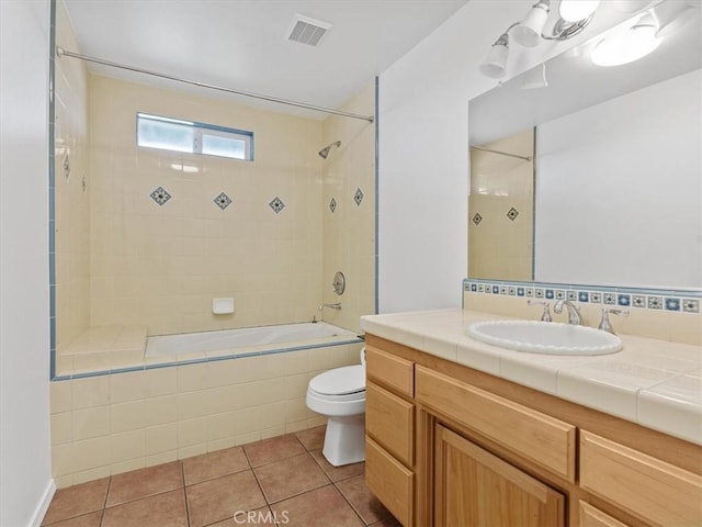 full bathroom with visible vents, toilet, tile patterned flooring, tiled shower / bath, and vanity