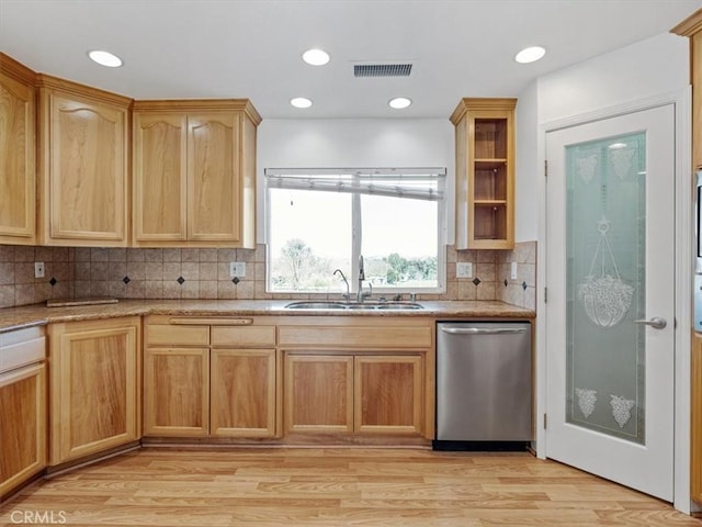 kitchen featuring visible vents, dishwasher, light countertops, light wood-type flooring, and a sink