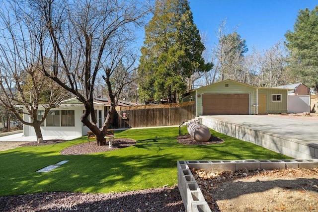 view of yard with an attached garage, fence, and driveway