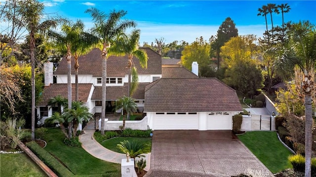 view of front of property featuring stucco siding, driveway, a chimney, and a front yard