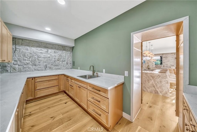 kitchen with light countertops, light brown cabinetry, light wood-style flooring, and a sink