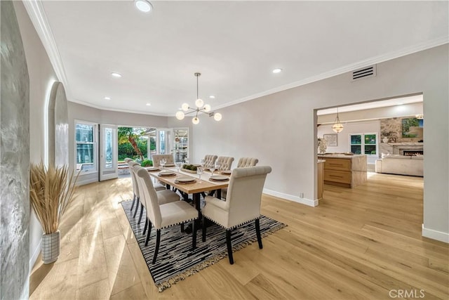 dining area with crown molding, light wood finished floors, baseboards, and visible vents