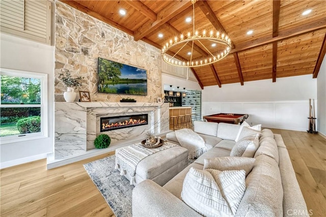 living room featuring a premium fireplace, a notable chandelier, wooden ceiling, wood finished floors, and beam ceiling