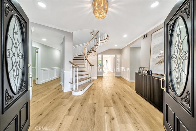 foyer featuring stairs, visible vents, crown molding, light wood finished floors, and an inviting chandelier