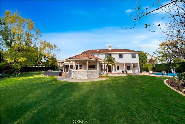 rear view of house featuring a yard, a patio area, an outdoor pool, and a chimney