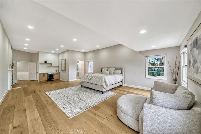 bedroom with wine cooler, baseboards, and light wood-type flooring