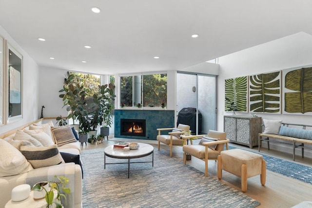 living room featuring a warm lit fireplace, expansive windows, wood finished floors, and recessed lighting